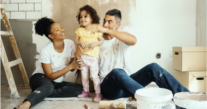 Parents with young daughter sitting on floor surrounded by renovation materials