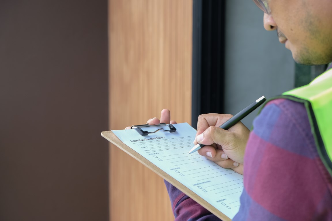 Asbestos assessor onsite making notes on a clipboard