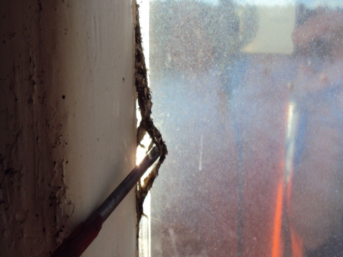 Close up of old asbestos rope that is detaching from a window 