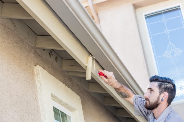 Man  painting the eaves of a house