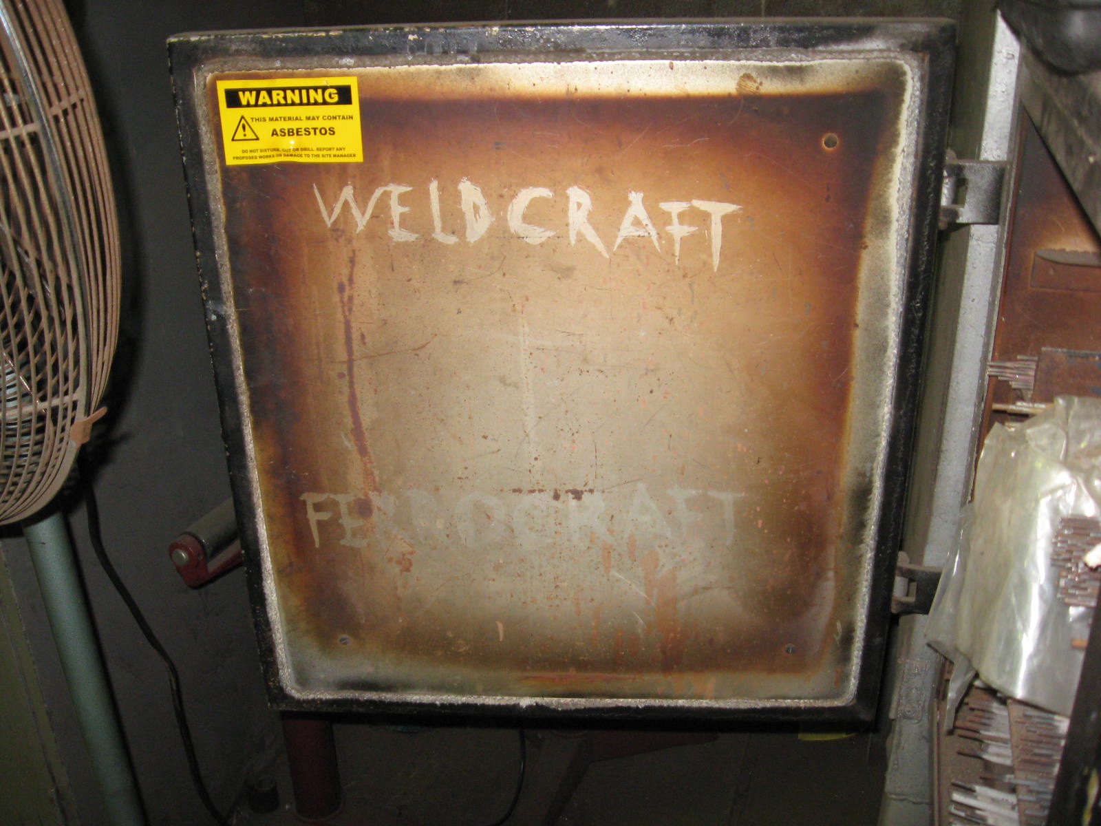 Close up of an oven door with asbestos tape around edge.