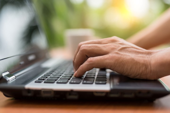 Close of a mans hand typing on a laptop