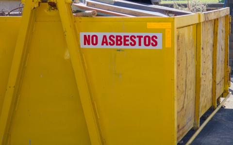 Large yellow industrial waste bin with no asbestos sign on it